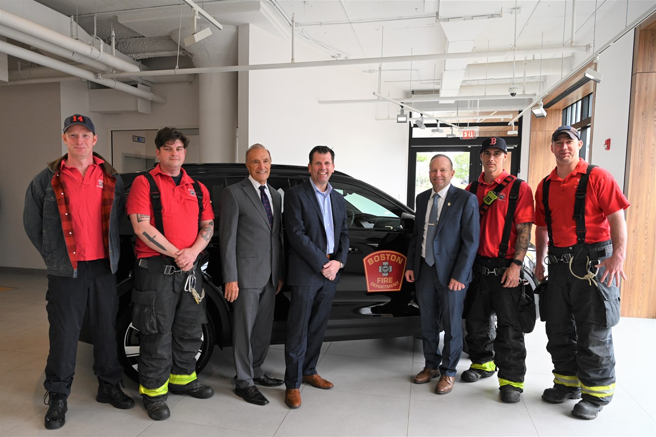 Eric Miller, Vice President Northeast Region, Volvo Car USA, center, with Jack Dempsey, Boston Fire Department Fire Commissioner (right) and Ray Ciccolo, Founder, Village Automotive Group (left), at Boston Volvo Cars in Allston with members of the Boston Fire Department and the Volvo XC40 Recharge electric SUV the company provided for rescue training.