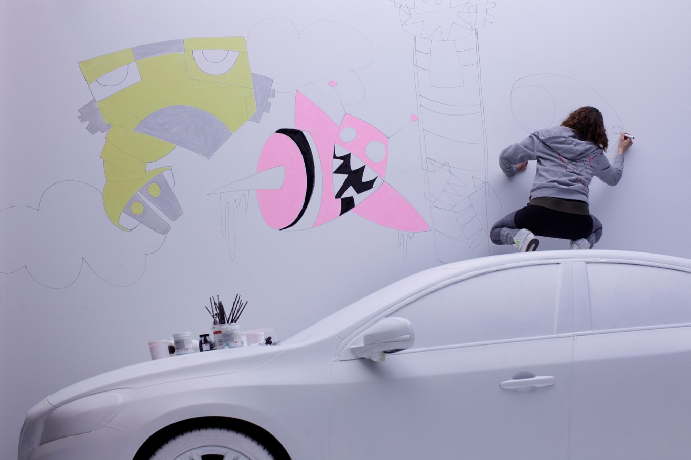 The artist C-Line is painting a Volvo S60 and the white wall behind